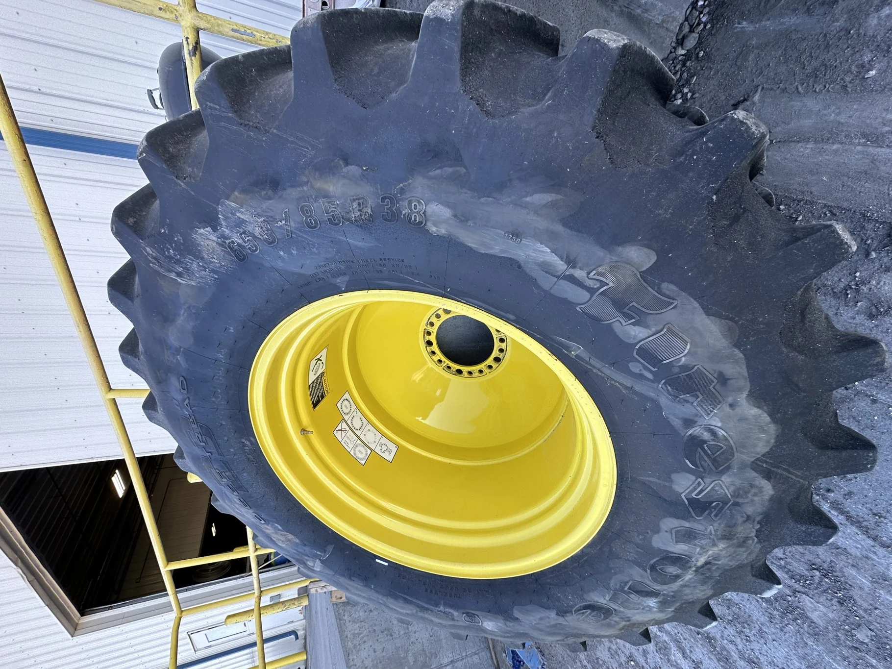 Used 87% 650/85R38 Firestone Radial Deep Tread 23 R-1W 173B TL on a 23 X 38 John Deere Yellow 20 Bol
